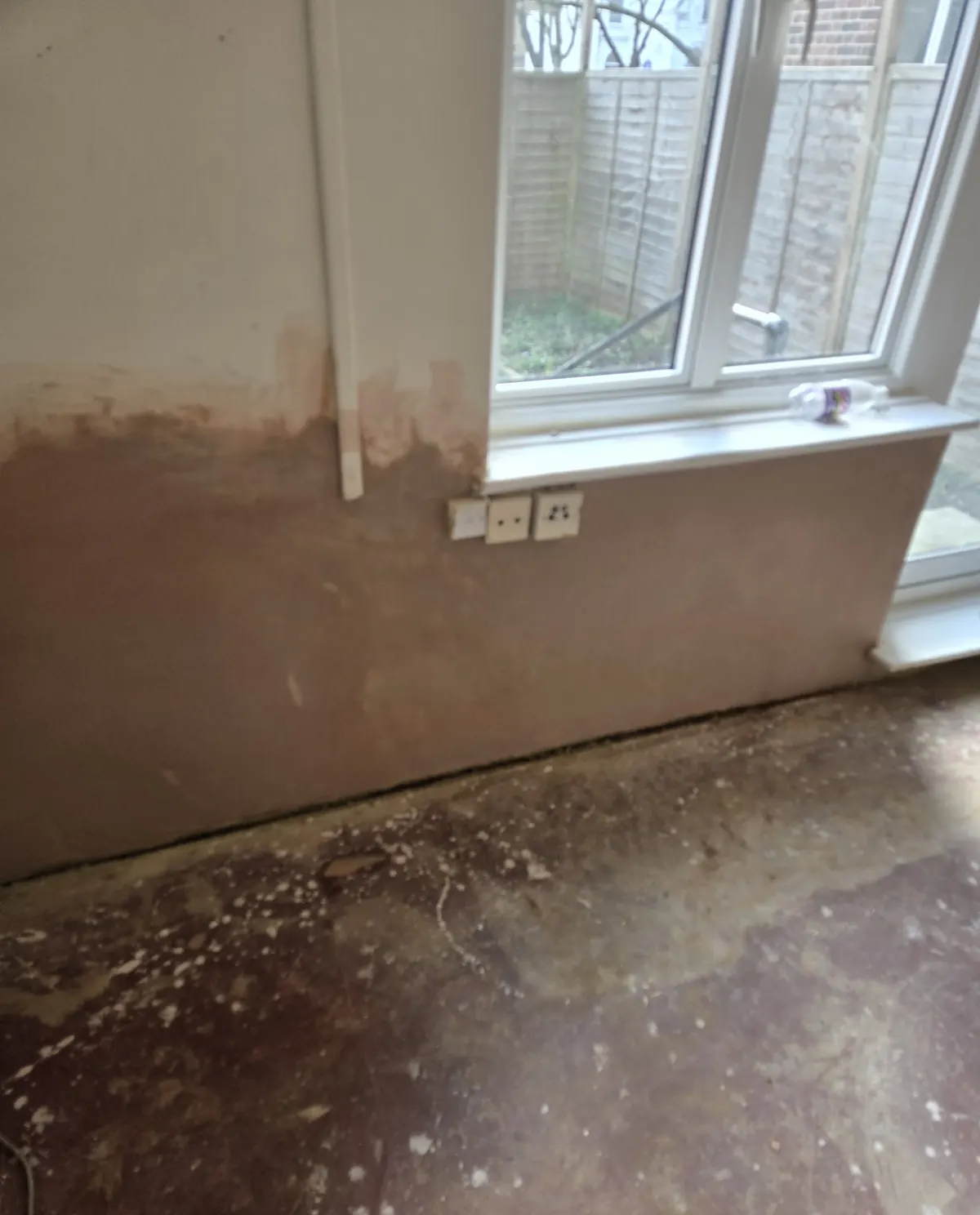 A repaired lower wall with a fresh skim coat drying